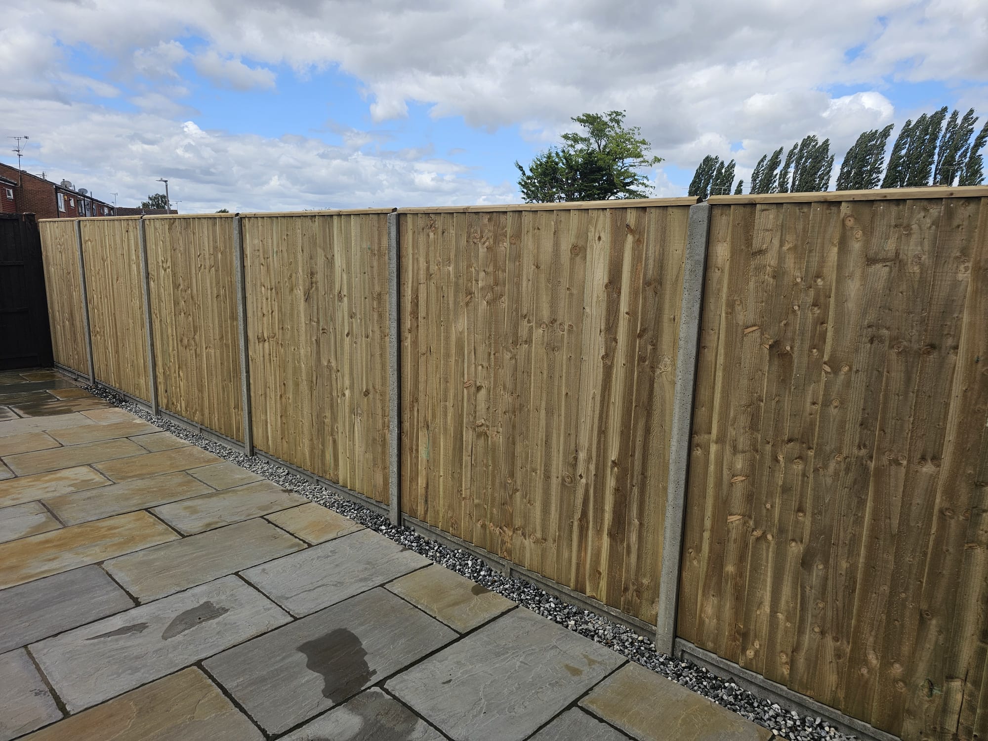 Professional closeboard fence installation with concrete posts alongside sandstone patio in Milton Keynes